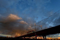 夕日に照らされた雪雲に向かって進むチン電