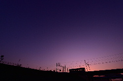 雲の無い夕日をバックに進むモ161形